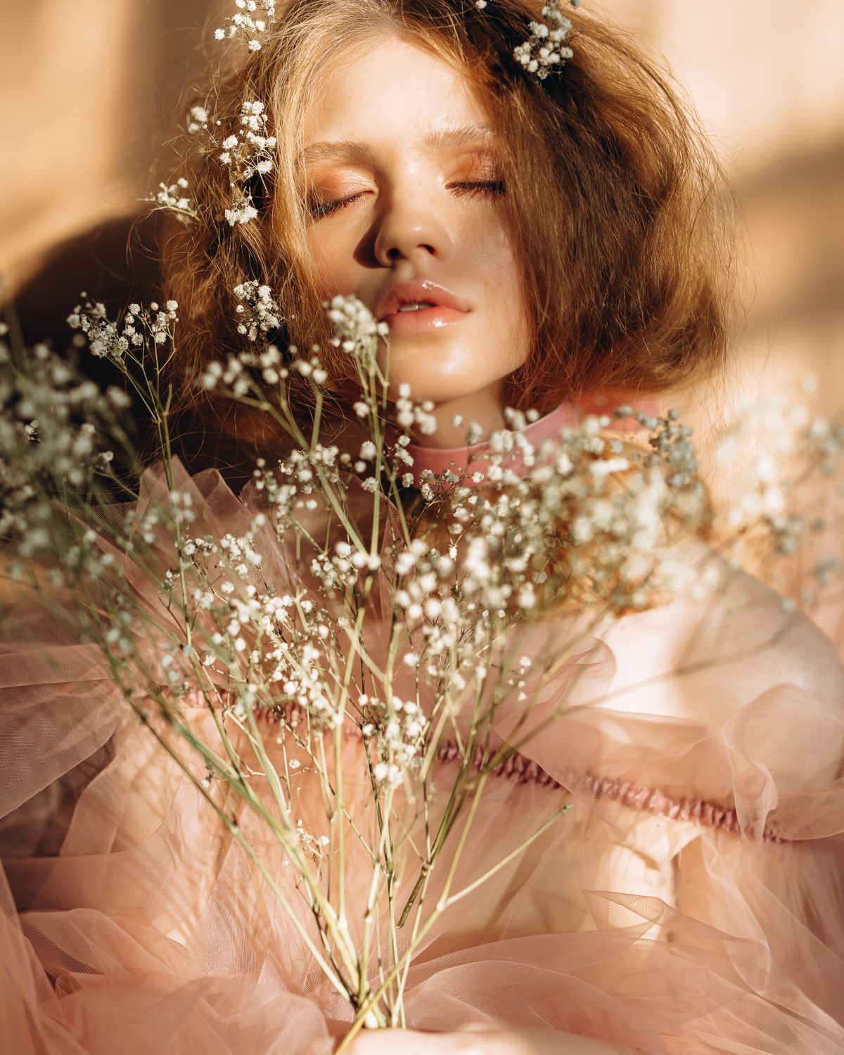 Woman lying among dried gypsophila in warm afternoon light.