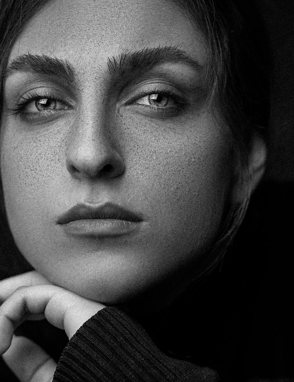 Close black and white portrait of a woman looking into the lens.
